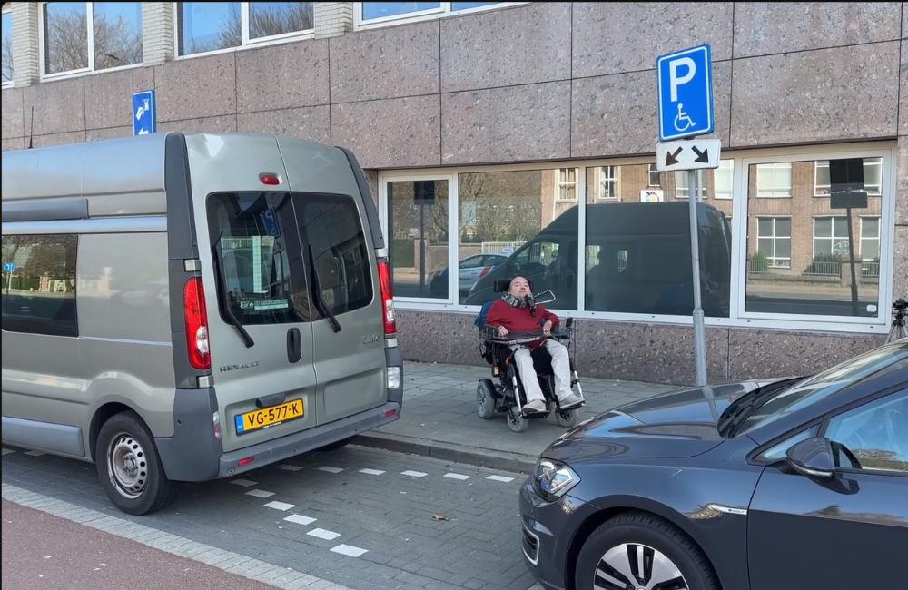 Man in rolstoel bij een invalidenparkeerplaats