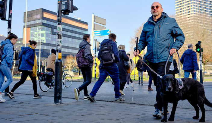 Man met blindengeleidehond op plein